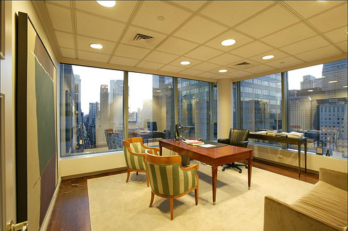 The CEO's sparten corner office at 535 Madison Avenue, with interior lighting and a North-view of dusk in the Big Apple.